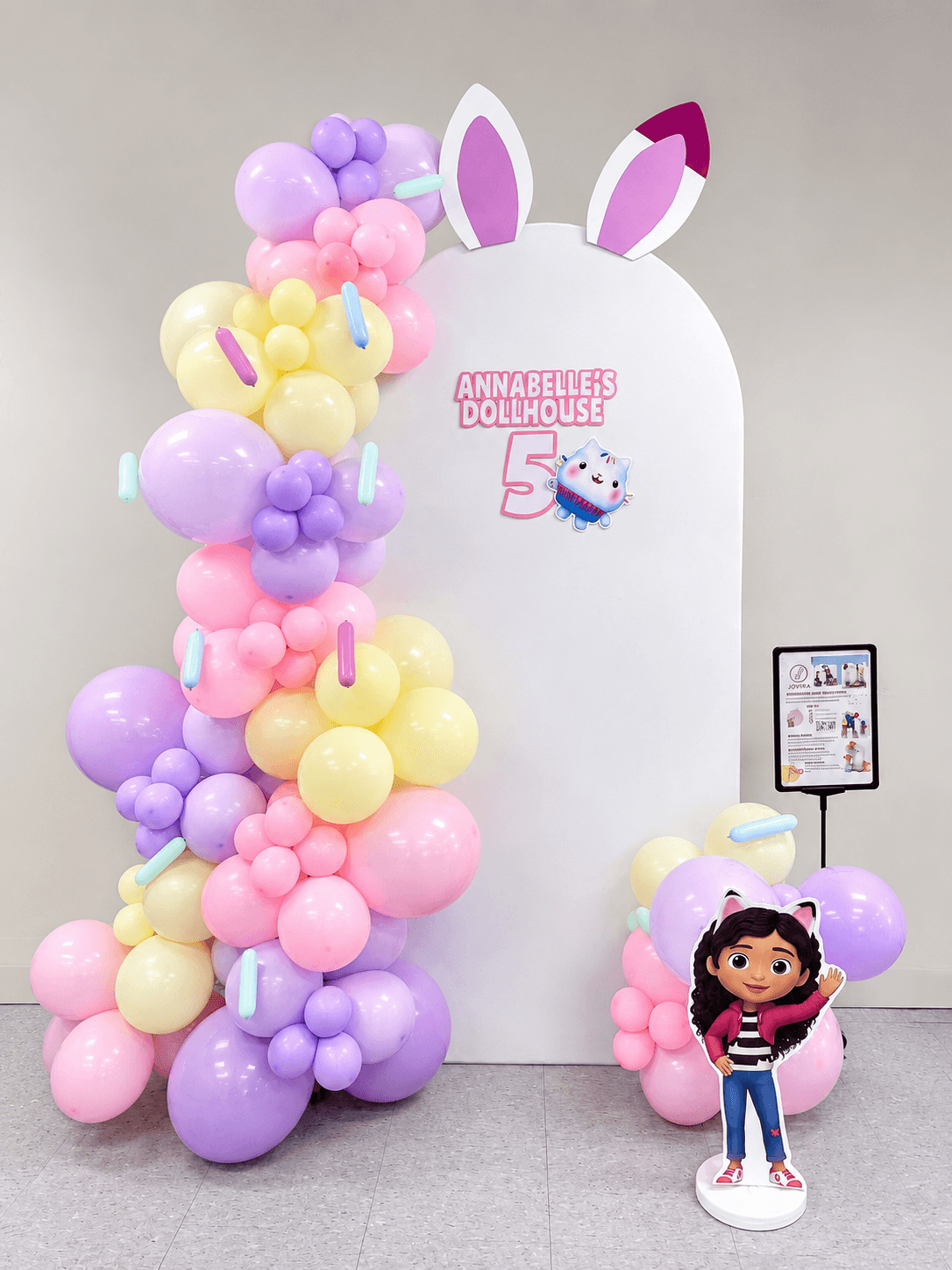 Blush and gold birthday lounge with layered balloons and a soft arch backdrop